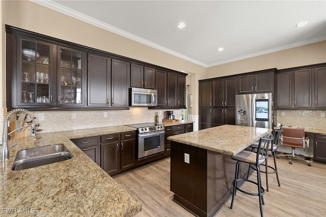5158 Roma St, Ave Maria, FL 34142 - kitchen with stainless steel appliances, a breakfast bar, a center island, light stone countertops, and dark brown cabinets