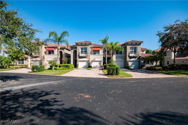 12085 Via Siena Ct Unit 102, Bonita Springs, FL 34135 - mediterranean / spanish-style home featuring an attached garage, stucco siding, driveway, and a tile roof