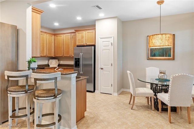 12085 Via Siena Ct Unit 102, Bonita Springs, FL 34135 - kitchen featuring stainless steel fridge, a peninsula, dark stone countertops, a breakfast bar area, and recessed lighting