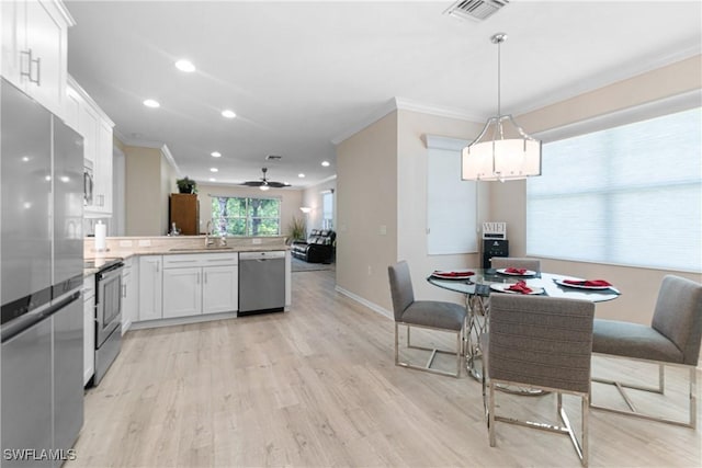 10736 Cetrella Dr, Fort Myers, FL 33913 - kitchen featuring appliances with stainless steel finishes, ornamental molding, a peninsula, white cabinetry, and light wood-style flooring