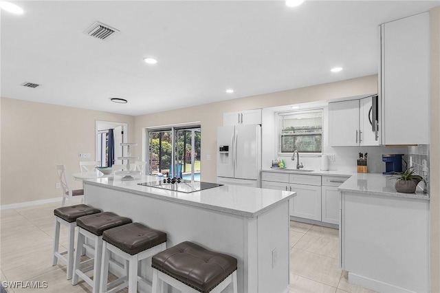 3823 Palm Tree Blvd, Cape Coral, FL 33904 - kitchen with white fridge with ice dispenser, black electric cooktop, a breakfast bar area, a kitchen island, and recessed lighting