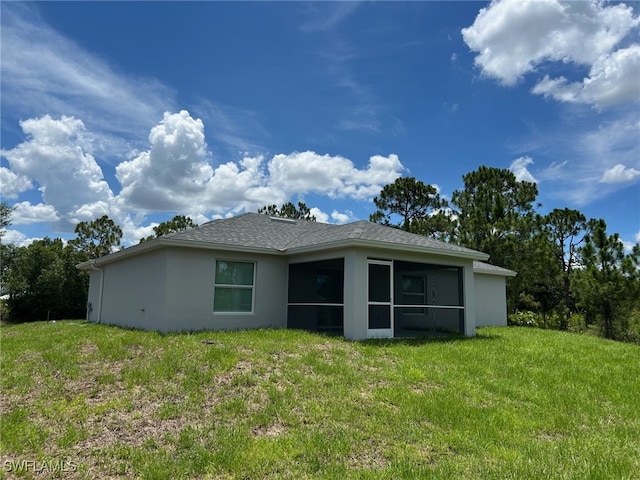 700 Avondale St E, Lehigh Acres, FL 33974 - rear view of house featuring stucco siding, a lawn, a sunroom, and roof with shingles