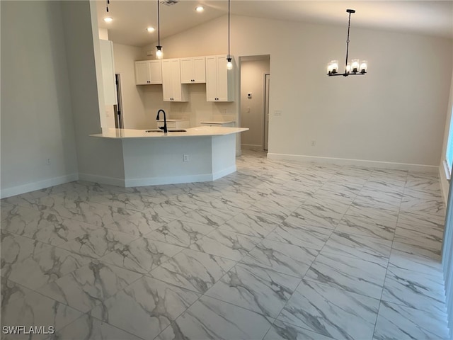 700 Avondale St E, Lehigh Acres, FL 33974 - kitchen with light marble finish floors, a chandelier, white cabinetry, vaulted ceiling, and recessed lighting