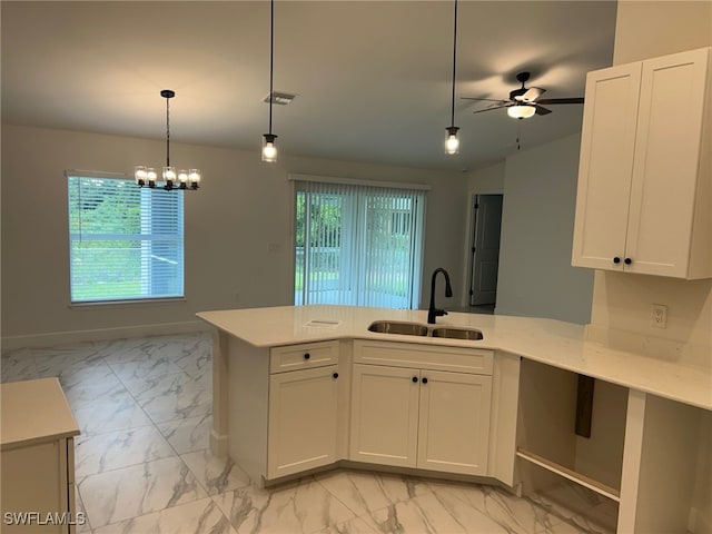 700 Avondale St E, Lehigh Acres, FL 33974 - kitchen featuring light marble finish floors, light countertops, ceiling fan, a peninsula, and white cabinets