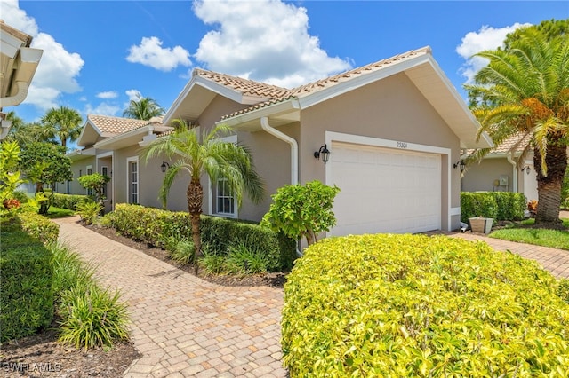 23204 Coconut Shores Dr, Estero, FL 34134 - view of side of home featuring stucco siding, a garage, a tile roof, and driveway