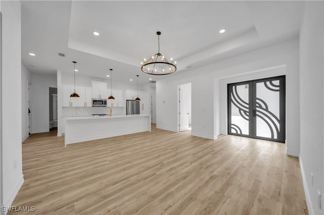 1517 Washington Ave, Lehigh Acres, FL 33972 - unfurnished living room with a tray ceiling, a chandelier, recessed lighting, and light wood finished floors