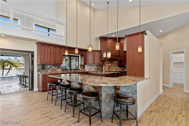 1701 Casey Key Dr, Punta Gorda, FL 33950 - kitchen with a towering ceiling, light wood-style floors, a breakfast bar area, stone counters, and recessed lighting