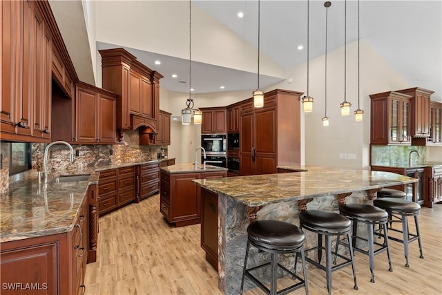 1701 Casey Key Dr, Punta Gorda, FL 33950 - kitchen with a center island with sink, light wood-style floors, tasteful backsplash, hanging light fixtures, and high vaulted ceiling