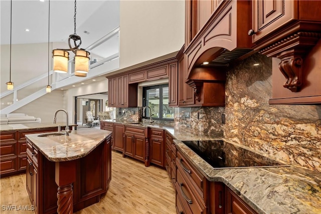 1701 Casey Key Dr, Punta Gorda, FL 33950 - kitchen featuring black electric cooktop, light wood finished floors, light stone counters, backsplash, and a high ceiling