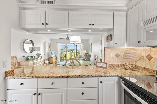 21 High Point Cir E Unit 308, Naples, FL 34103 - kitchen featuring stainless steel electric range oven, white cabinetry, white microwave, backsplash, and light stone counters