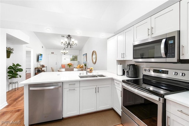 4945 Cougar Ct S Unit 4-202, Naples, FL 34109 - kitchen featuring stainless steel appliances, a peninsula, light countertops, a chandelier, and white cabinetry