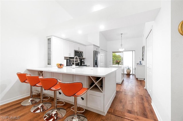 4945 Cougar Ct S Unit 4-202, Naples, FL 34109 - kitchen featuring stainless steel appliances, a peninsula, wood finished floors, glass insert cabinets, and a kitchen breakfast bar