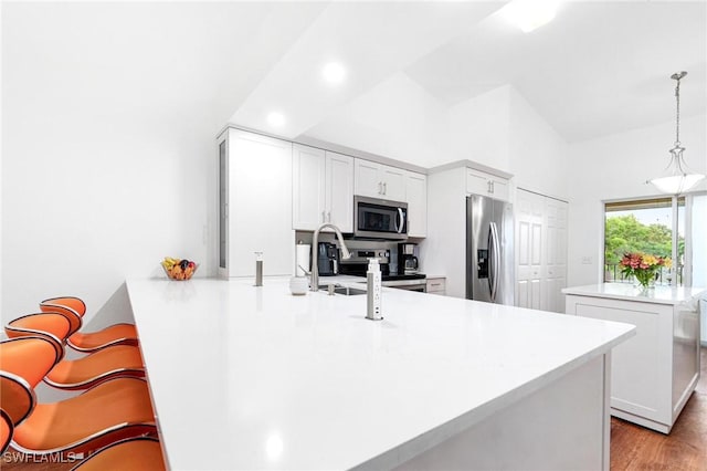 4945 Cougar Ct S Unit 4-202, Naples, FL 34109 - kitchen with appliances with stainless steel finishes, a peninsula, light countertops, a breakfast bar, and decorative light fixtures