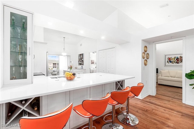 4945 Cougar Ct S Unit 4-202, Naples, FL 34109 - kitchen featuring a peninsula, light wood finished floors, a kitchen breakfast bar, light countertops, and vaulted ceiling