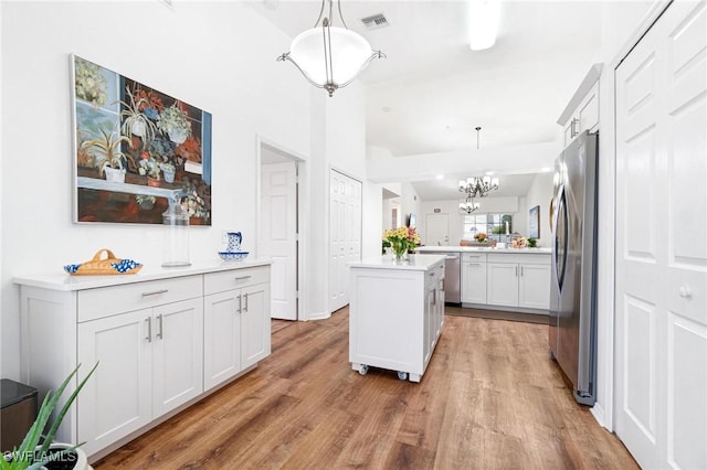 4945 Cougar Ct S Unit 4-202, Naples, FL 34109 - kitchen featuring appliances with stainless steel finishes, light wood finished floors, hanging light fixtures, light countertops, and a kitchen island