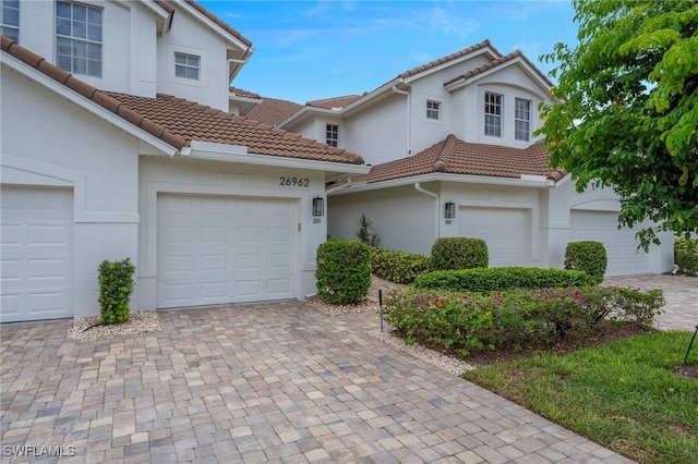 26962 Montego Pointe Ct Unit 202, Bonita Springs, FL 34134 - view of front of property with a tile roof, stucco siding, decorative driveway, and a garage