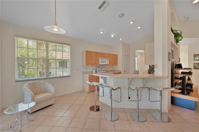 26962 Montego Pointe Ct Unit 202, Bonita Springs, FL 34134 - kitchen with white microwave, a kitchen breakfast bar, light countertops, light brown cabinetry, and vaulted ceiling