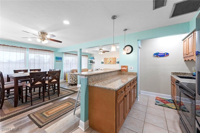 4938 Vincennes St Unit 3, Cape Coral, FL 33904 - kitchen featuring black range with electric stovetop, ceiling fan, a kitchen breakfast bar, light stone counters, and brown cabinets
