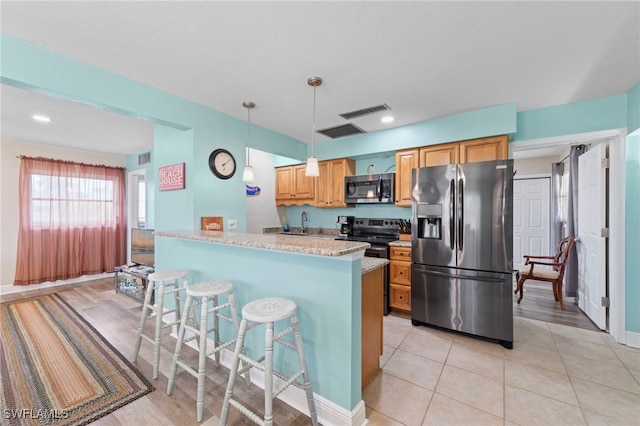 4938 Vincennes St Unit 3, Cape Coral, FL 33904 - kitchen with appliances with stainless steel finishes, a breakfast bar area, hanging light fixtures, a peninsula, and light tile patterned floors