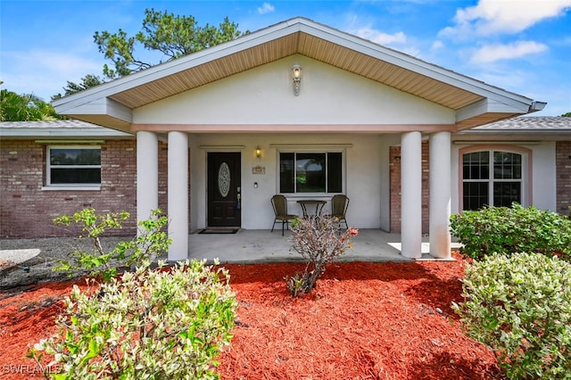 165 4th St, Bonita Springs, FL 34134 - view of front of house with a porch, brick siding, stucco siding, and roof with shingles