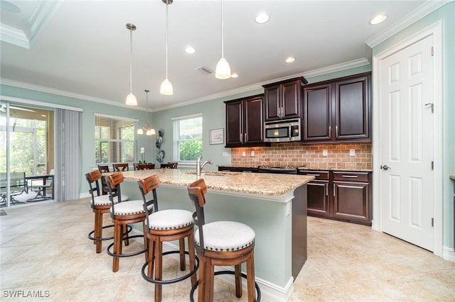 20551 Long Pond Rd, North Fort Myers, FL 33917 - kitchen with stainless steel microwave, a kitchen breakfast bar, decorative backsplash, light stone counters, and crown molding
