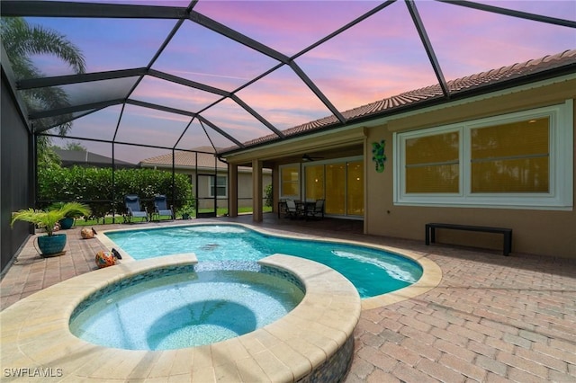 20551 Long Pond Rd, North Fort Myers, FL 33917 - pool at dusk featuring a patio area, a pool with connected hot tub, a ceiling fan, and glass enclosure