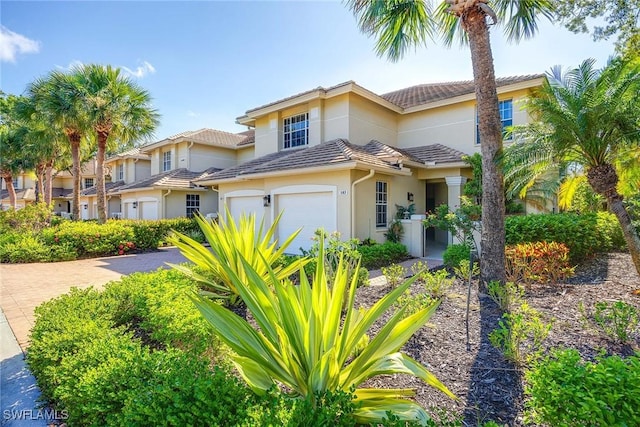 24400 Reserve Ct Unit 103, Bonita Springs, FL 34134 - view of front of house with stucco siding, a tiled roof, driveway, and an attached garage