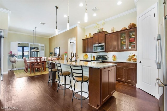14274 Arrow Point Ct, Estero, FL 33928 - kitchen featuring stainless steel appliances, dark wood finished floors, light stone counters, a center island with sink, and pendant lighting