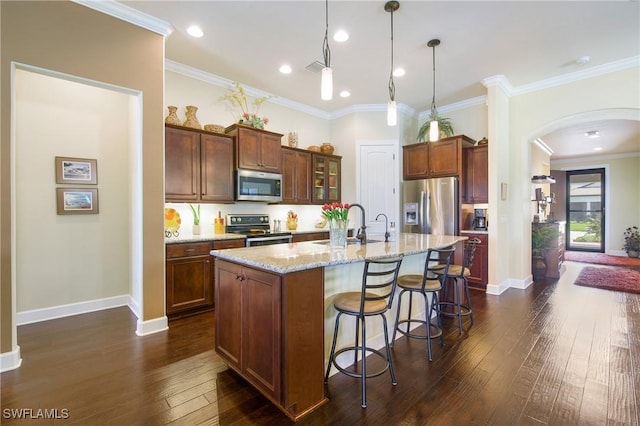 14274 Arrow Point Ct, Estero, FL 33928 - kitchen featuring stainless steel appliances, arched walkways, dark wood-type flooring, light stone countertops, and a center island with sink