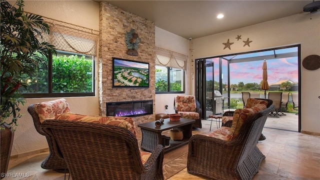14274 Arrow Point Ct, Estero, FL 33928 - living area with stone tile floors, a stone fireplace, recessed lighting, and a water view