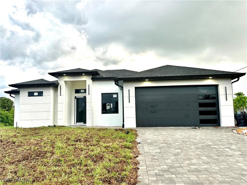 3201 2nd St SW, Lehigh Acres, FL 33976 - view of front of home with stucco siding, decorative driveway, and a garage