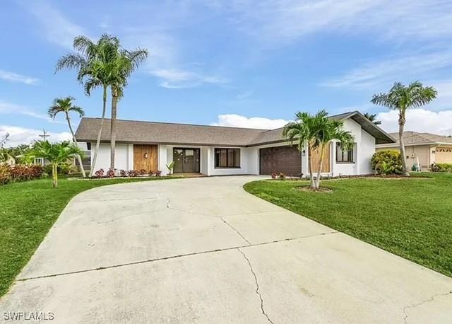 813 SW 52nd St, Cape Coral, FL 33914 - ranch-style house featuring curved driveway, a front lawn, and a garage