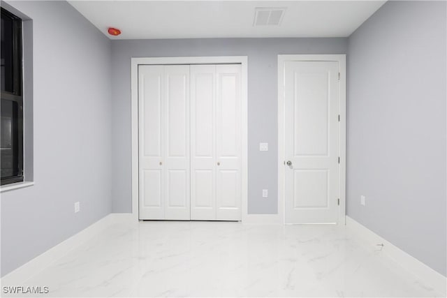 2714 2nd St SW, Lehigh Acres, FL 33976 - unfurnished bedroom with marble look tile flooring and a closet