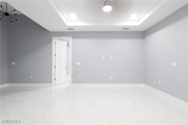 2714 2nd St SW, Lehigh Acres, FL 33976 - unfurnished room with a tray ceiling, marble finish flooring, and a chandelier