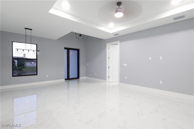 2714 2nd St SW, Lehigh Acres, FL 33976 - spare room with light marble finish flooring, a tray ceiling, and a ceiling fan