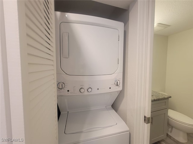 8313 Bernwood Cove Loop Unit 1211, Fort Myers, FL 33966 - washroom with estacked washer and dryer and a textured ceiling
