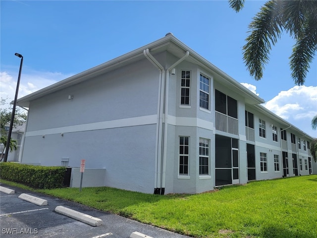 8313 Bernwood Cove Loop Unit 1211, Fort Myers, FL 33966 - view of home's exterior with stucco siding, uncovered parking, and a yard