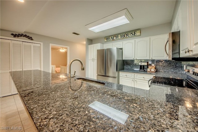 841 SW 47th Ter Unit 206, Cape Coral, FL 33914 - kitchen with appliances with stainless steel finishes, white cabinets, dark stone countertops, decorative backsplash, and light tile patterned floors