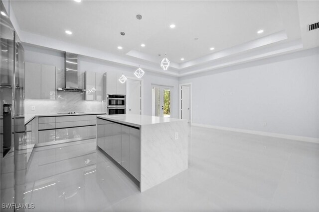 3990 27th Ave NE, Naples, FL 34120 - kitchen featuring modern cabinets, wall chimney exhaust hood, a raised ceiling, stainless steel double oven, and recessed lighting