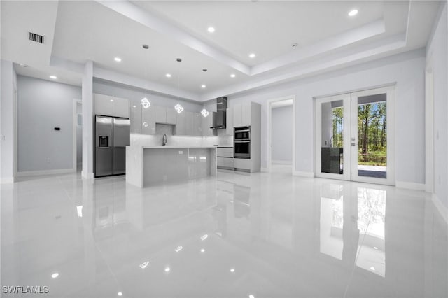 3990 27th Ave NE, Naples, FL 34120 - unfurnished living room with a tray ceiling, french doors, recessed lighting, and light tile patterned floors