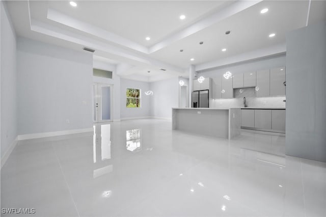 3990 27th Ave NE, Naples, FL 34120 - unfurnished living room featuring light tile patterned floors, recessed lighting, and a tray ceiling