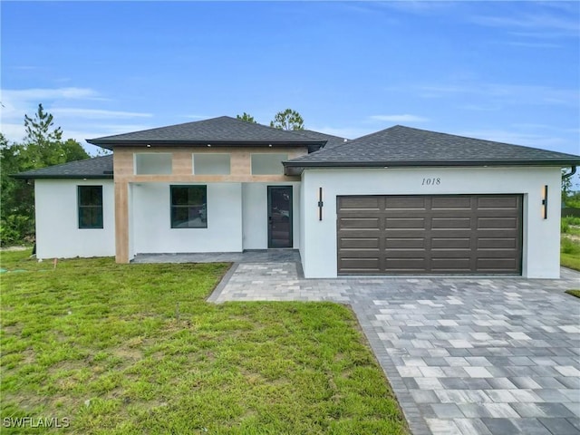 1018 Calvin Ave, Lehigh Acres, FL 33972 - prairie-style house featuring stucco siding, a garage, a front lawn, decorative driveway, and a shingled roof