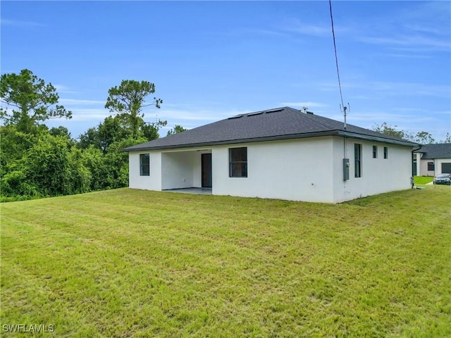 1018 Calvin Ave, Lehigh Acres, FL 33972 - rear view of property with stucco siding and a lawn