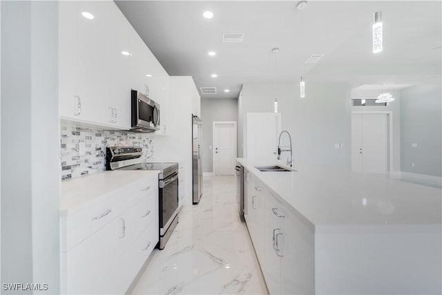 4002 22nd St SW, Lehigh Acres, FL 33976 - kitchen with stainless steel appliances, light marble finish flooring, backsplash, white cabinetry, and a large island