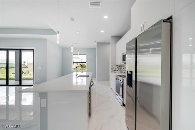 4002 22nd St SW, Lehigh Acres, FL 33976 - kitchen with stainless steel appliances, modern cabinets, light marble finish floors, white cabinetry, and decorative backsplash