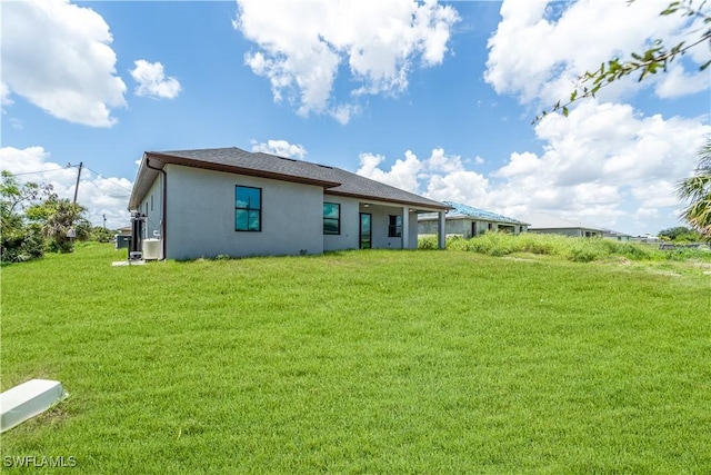 4002 22nd St SW, Lehigh Acres, FL 33976 - rear view of house with stucco siding and a lawn