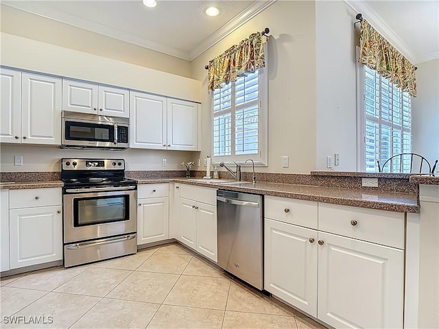 2050 Rio Nuevo Dr, North Fort Myers, FL 33917 - kitchen featuring appliances with stainless steel finishes, crown molding, light tile patterned flooring, dark countertops, and white cabinetry