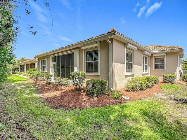 2050 Rio Nuevo Dr, North Fort Myers, FL 33917 - view of property exterior featuring stucco siding, a tiled roof, and a lawn