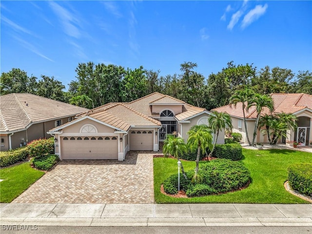 2050 Rio Nuevo Dr, North Fort Myers, FL 33917 - mediterranean / spanish home with a garage, decorative driveway, a front lawn, stucco siding, and a tiled roof