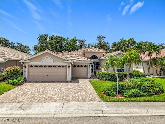 2050 Rio Nuevo Dr, North Fort Myers, FL 33917 - mediterranean / spanish-style home with stucco siding, an attached garage, decorative driveway, and a tiled roof
